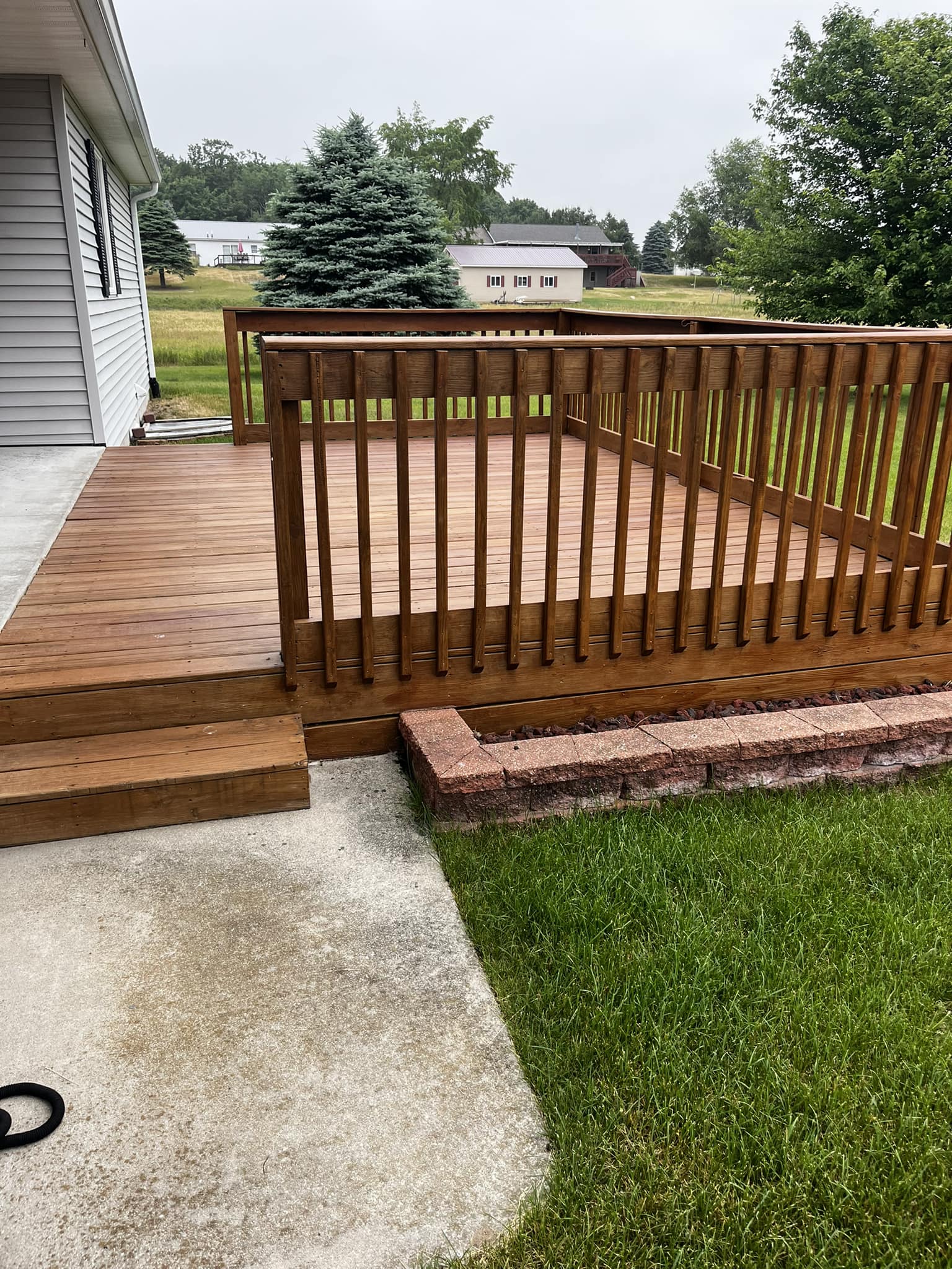 Clean deck with stained railing and brick steps after deck washing by Lawndash Powerwashing in Mt. Pleasant Michigan